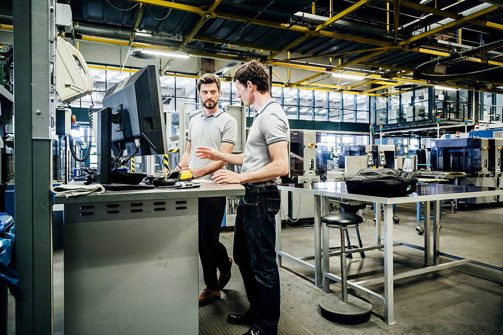 two men at a computer in a manufacturing setting