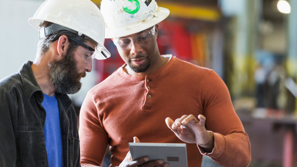 men in hard hats looking at screen 