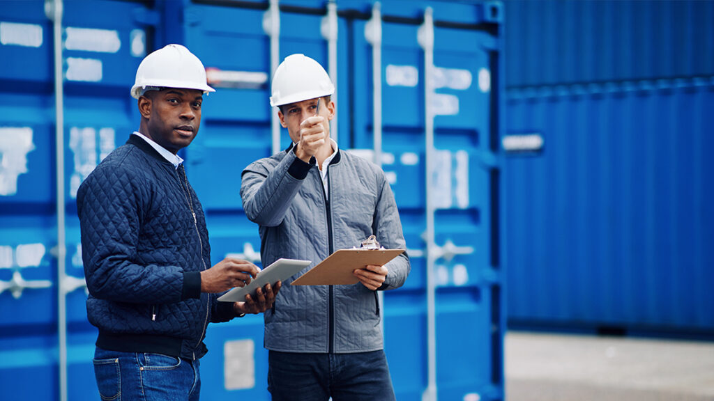 two men in front of shipping containers