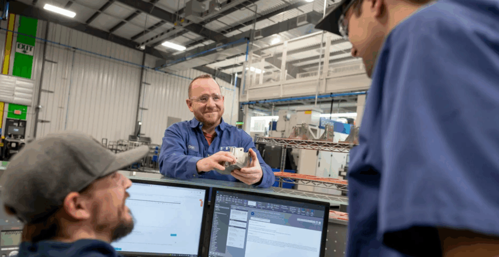 Team members at FPD company talk near a computer.